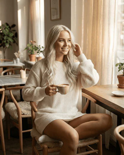 Aurora Mini Dress by Lauven, white ribbed knit off-the-shoulder style worn in a cozy cafe setting.