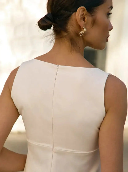 Elegant back view of a woman in a soft white mini dress featuring a round neckline and a subtle zip closure.