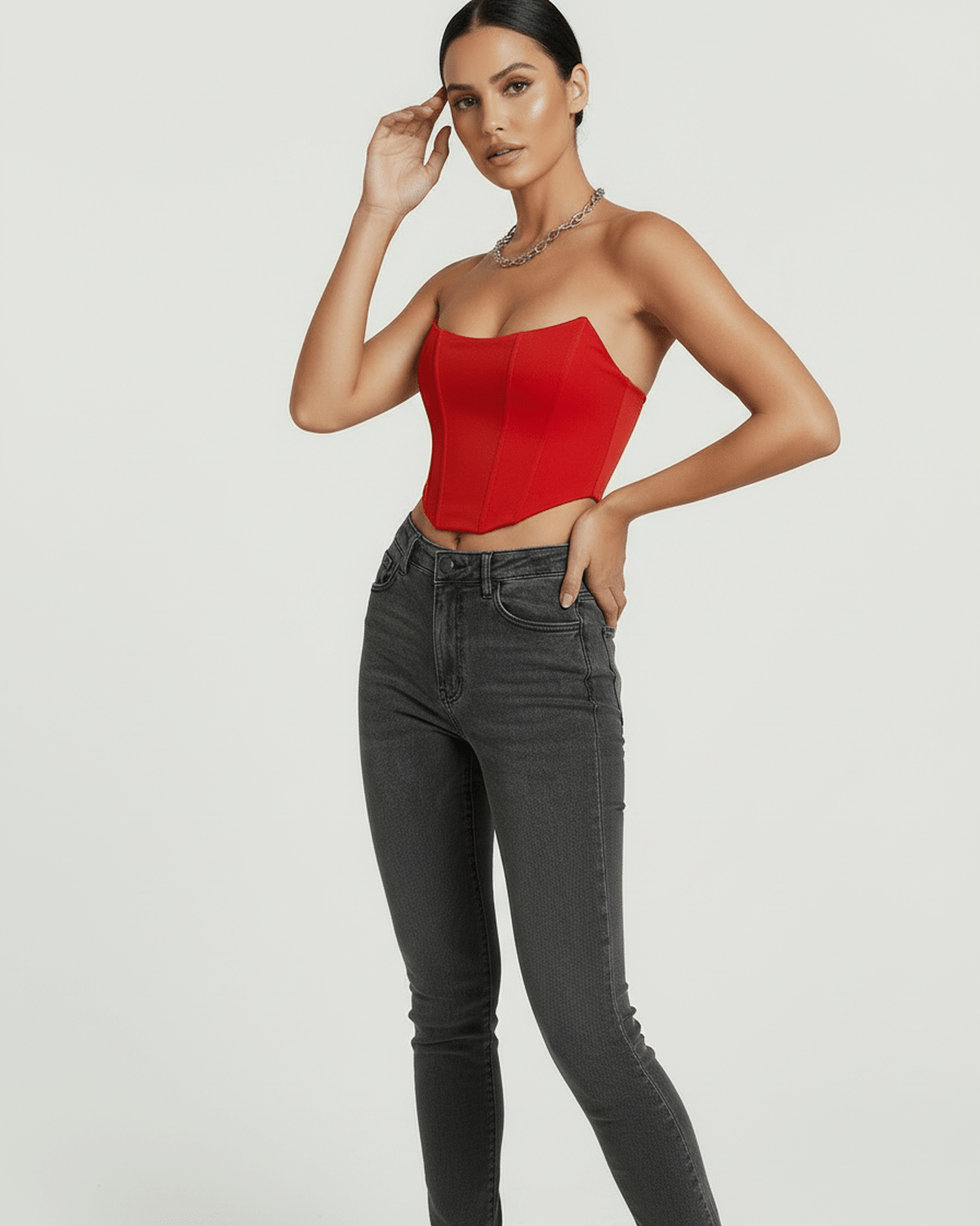Model wearing the Solara Corset Top by Lauven in vibrant red velvet, styled with high-waisted jeans.