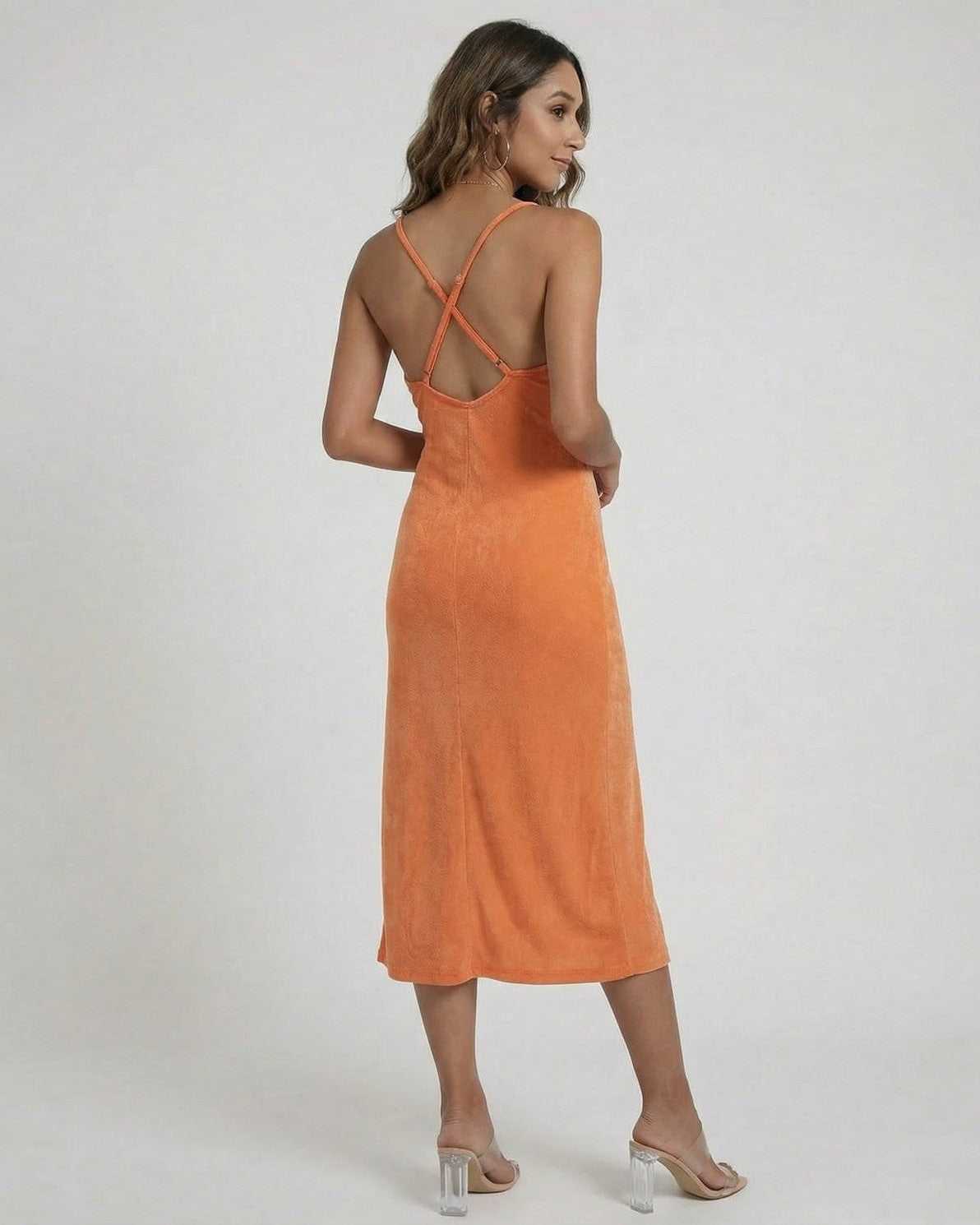 Model showcasing the back view of the Solara Midi Dress by Lauven in vibrant orange with cross-back straps.