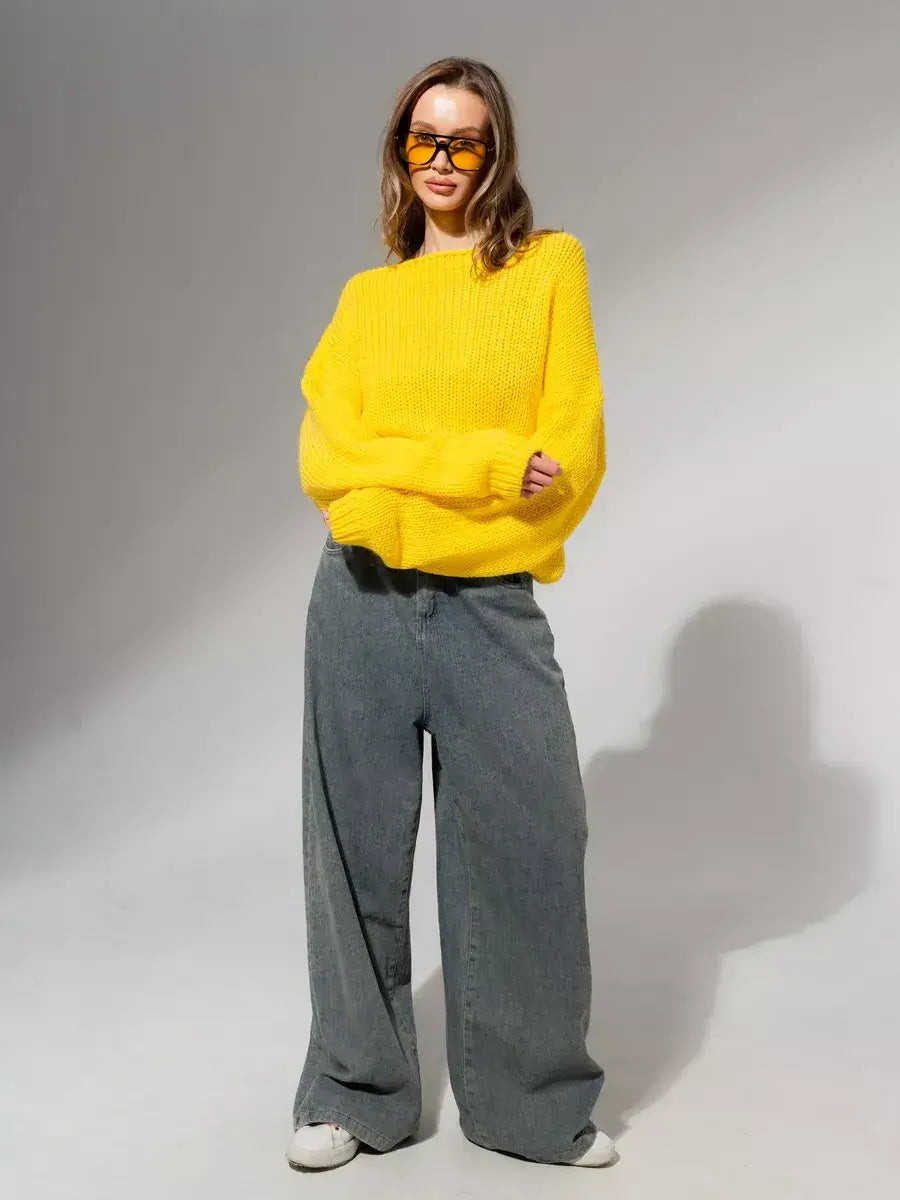 Model wearing Solara Sweater by Lauven in bright yellow, paired with wide-leg jeans and sunglasses.