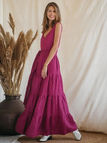 Model showcasing the Solène Maxi Dress in magenta, featuring a V-neckline, tiered design, and backless style against soft background.