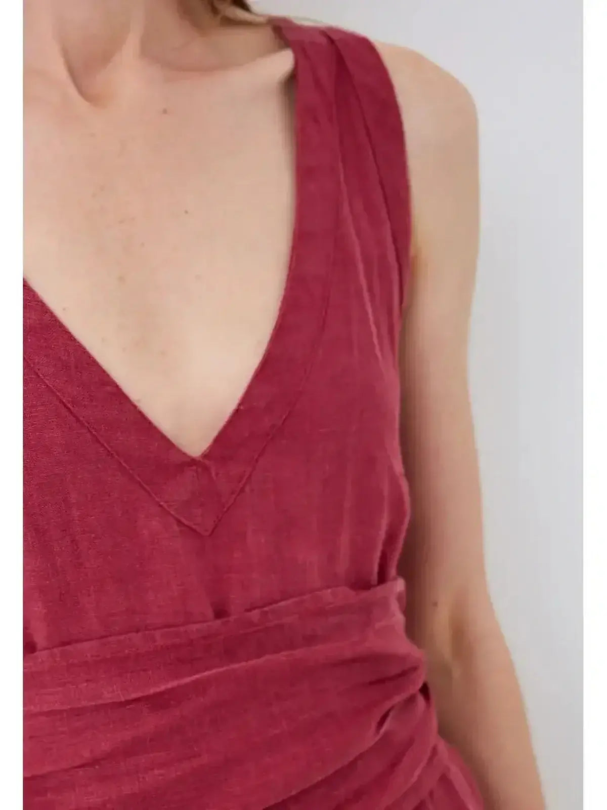 Close-up of Solène Maxi Dress in rich burgundy showcasing V-neckline and cinched wrap waist in natural linen.