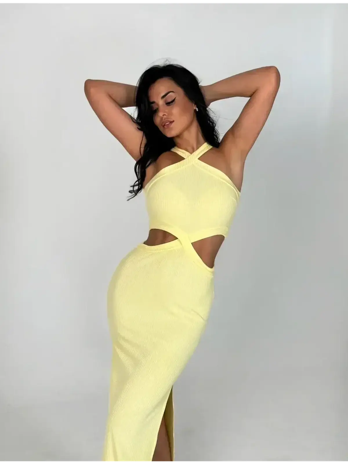 Model wears Sunlace Midi Dress in pastel yellow, featuring sculptural cutouts and a fitted silhouette for a chic look.