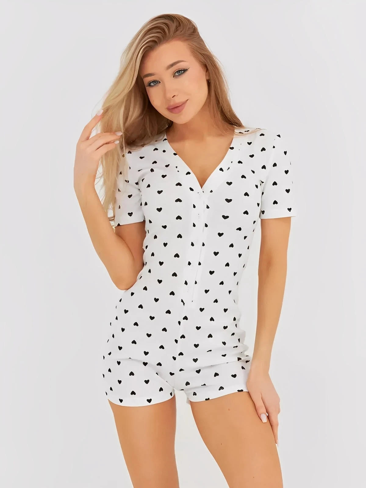 Model wearing a white and black heart print ribbed playsuit with a V-neck and button front.