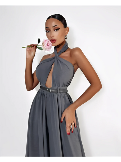 Woman wearing a grey Twist Halter Jumpsuit with open back and wide legs, posing with a flower.