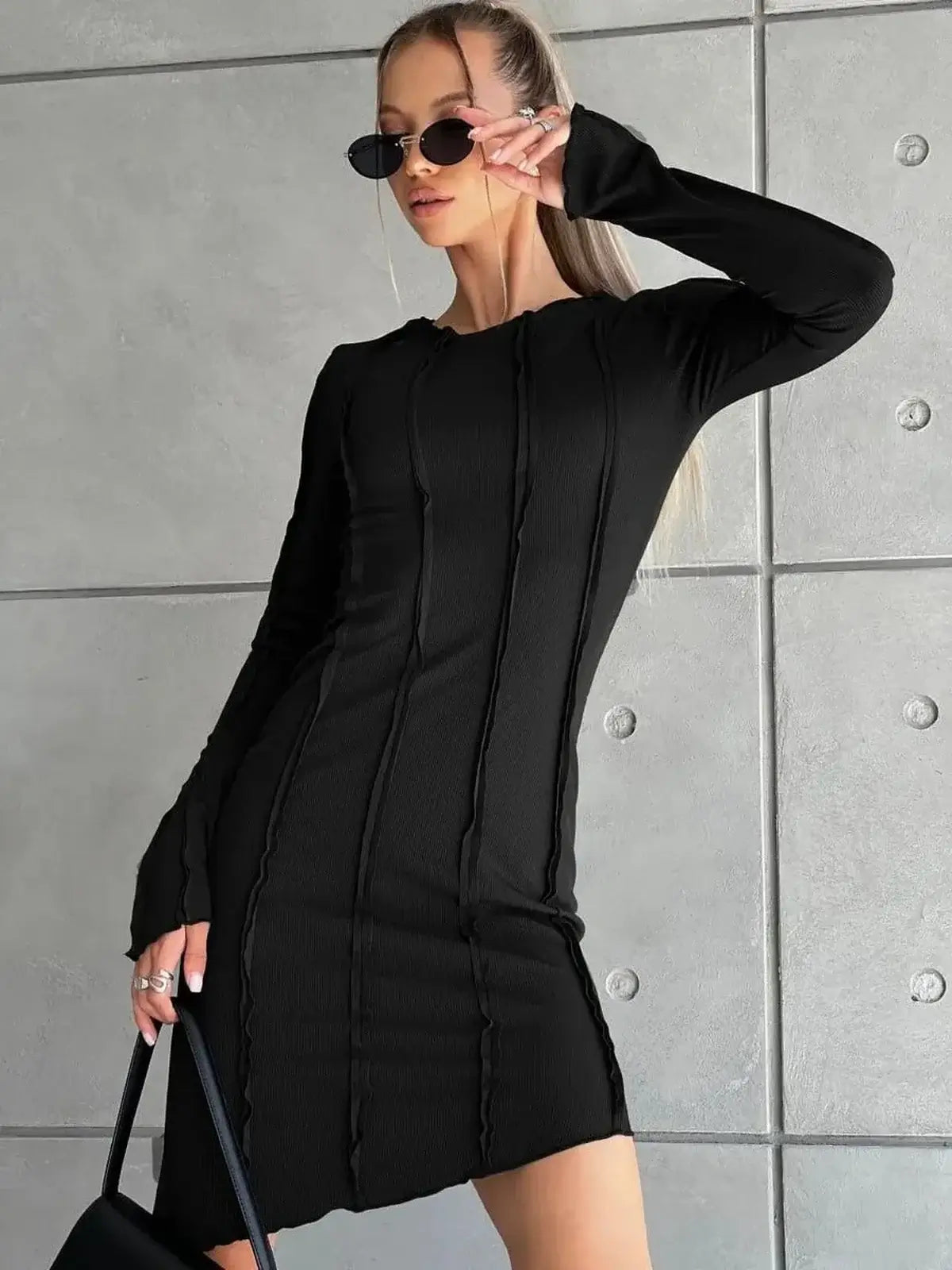 Ultra-modern black mini dress with long sleeves, curve-contouring seams, and an edgy silhouette.