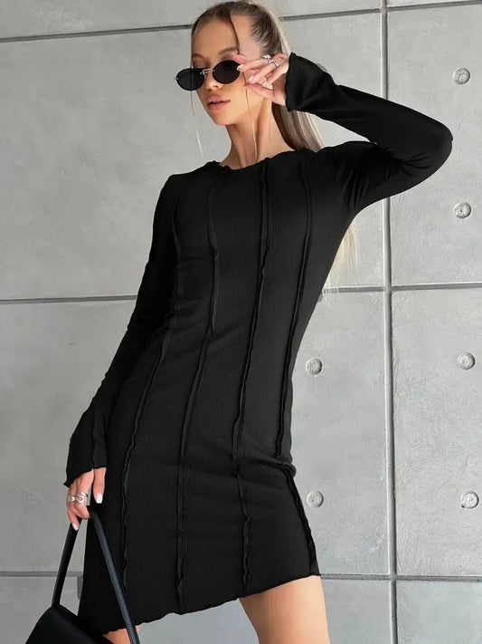 Ultra-modern black mini dress with long sleeves, curve-contouring seams, and an edgy silhouette.