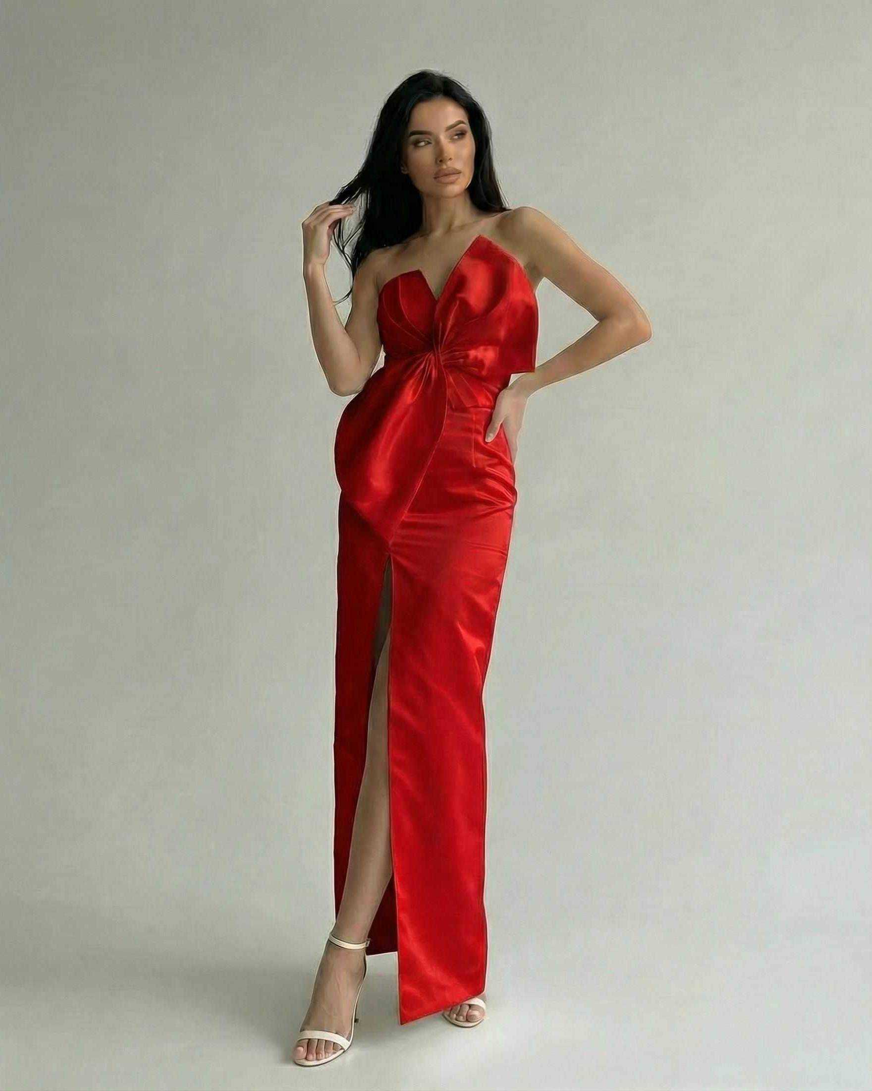 Elegant woman wearing Lauven Valencia Maxi Dress in red satin with front slit and sculptural neckline.