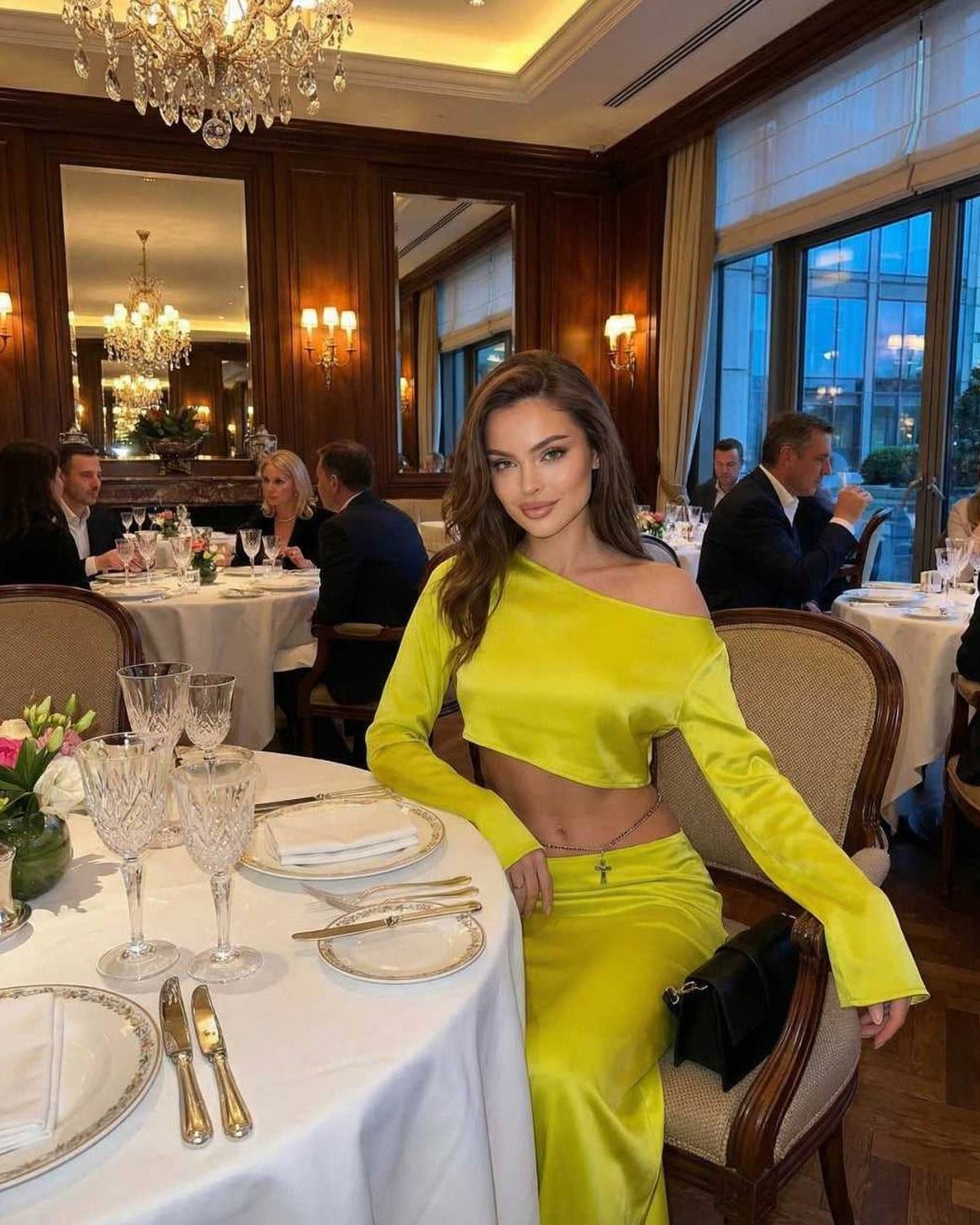 Vega Midi Dress by Lauven in vibrant yellow, model posing elegantly at a dinner table, showcasing modern club-ready style.
