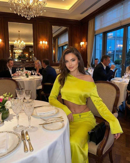 Vega Midi Dress by Lauven in vibrant yellow, model posing elegantly at a dinner table, showcasing modern club-ready style.