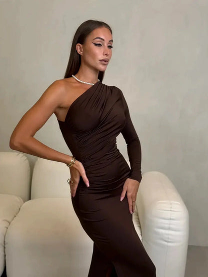 Model wearing Velour Muse Maxi Dress in chocolate brown with one-shoulder design and ruched silhouette.