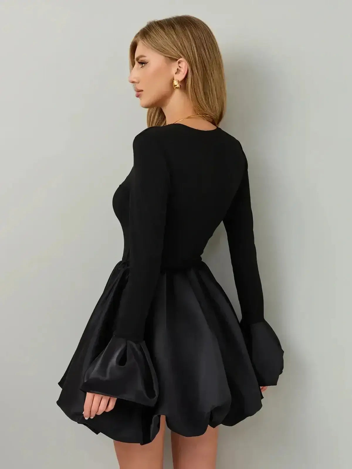 Elegant woman wearing the Velvet Bloom black dress, featuring a soft knit bodice and satin balloon skirt.