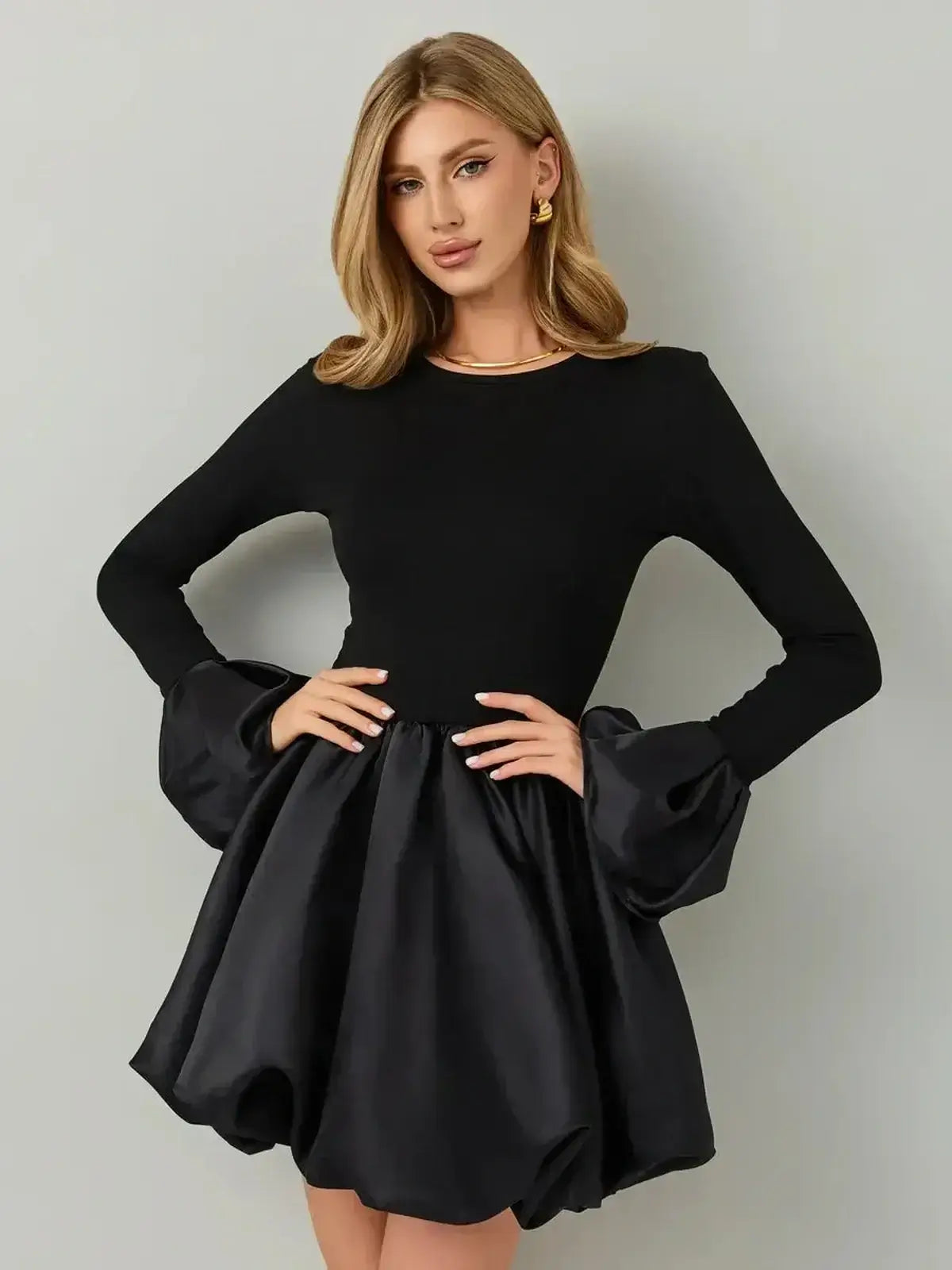 Black mini dress with a soft knit bodice and satin balloon skirt, long sleeves with exaggerated cuffs.
