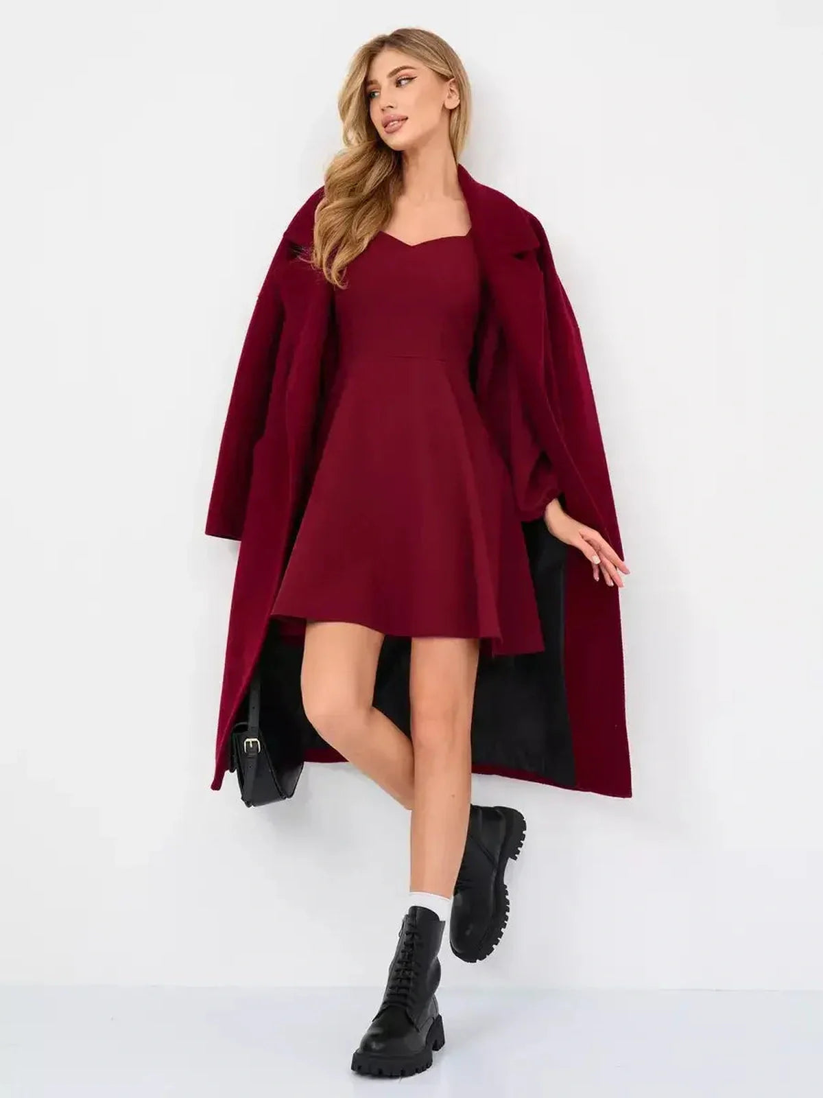 Model showcasing Velvet Bloom burgundy mini dress with dramatic long sleeves and stylish coat, perfect for parties.