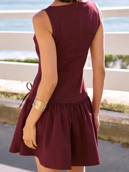 Back view of a sleeveless burgundy mini dress with a pleated skirt, perfect for summer and evening parties.