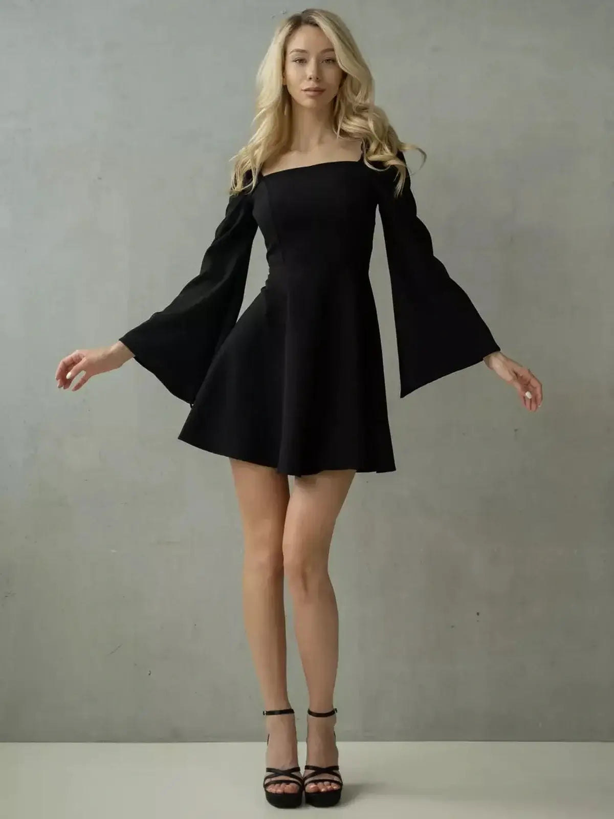 Modern black mini dress with flared sleeves and structured square neckline, perfect for weddings and formal events.