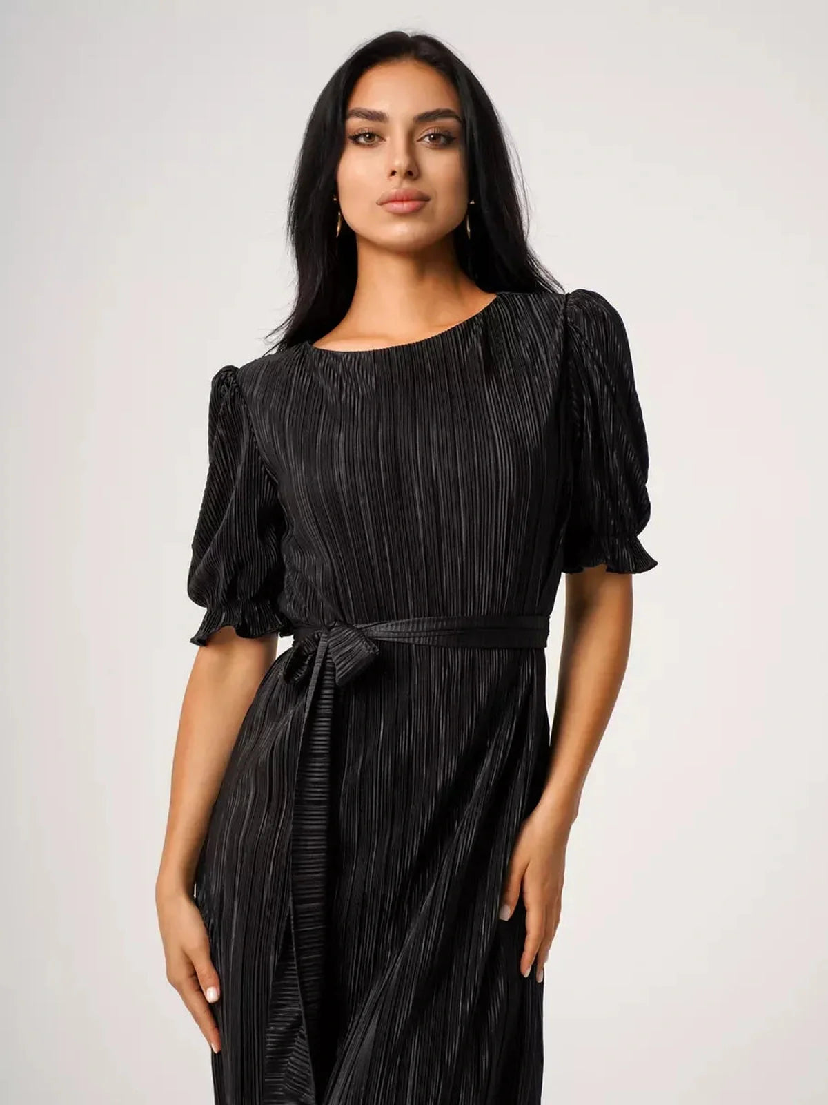 Model wearing a black Velvet Rhythm Maxi Dress with puff sleeves and pleated texture, showcasing its elegant silhouette.