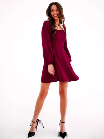 Stylish woman in a deep burgundy mini dress with long sleeves, perfect for formal events and wedding guest attire.