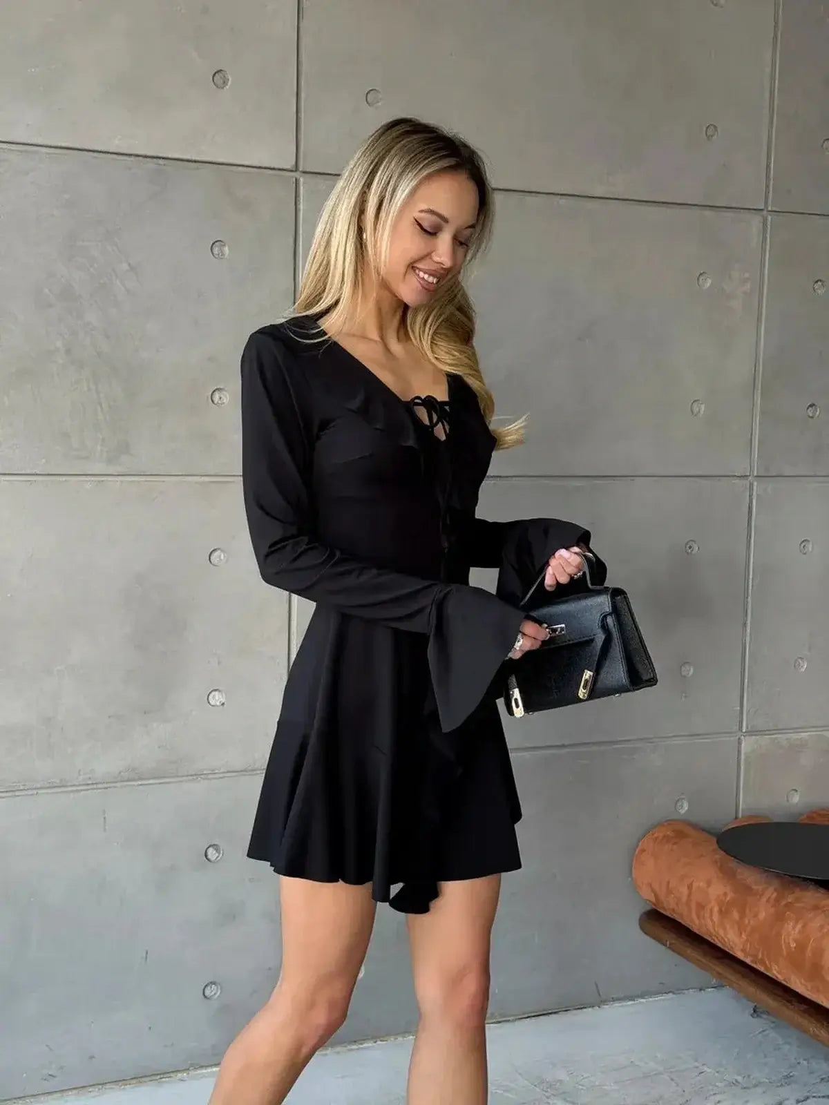 Black mini dress with long sleeves, V-neckline, and ruffle accents perfect for parties and special events.