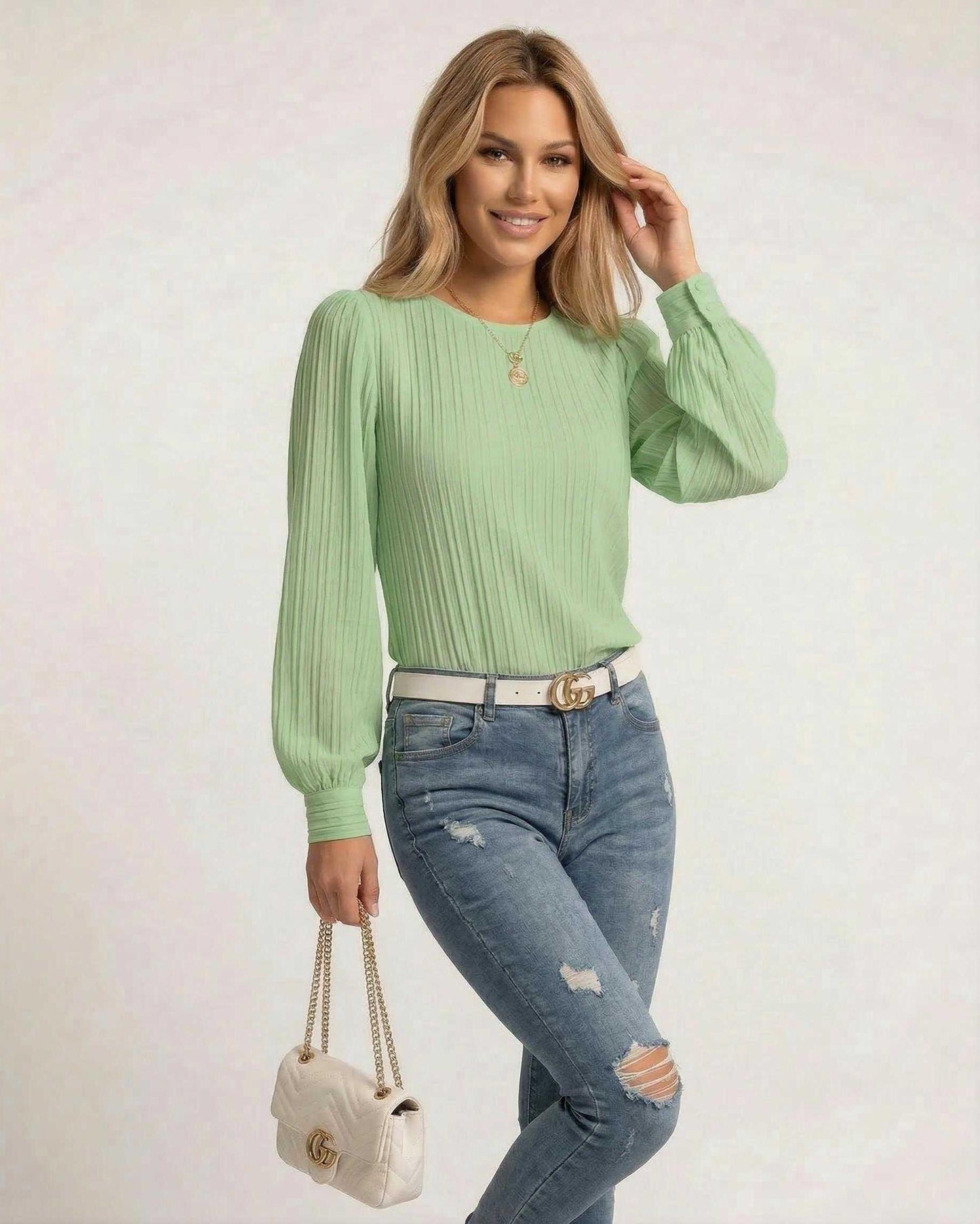 Model wearing a Verde Blouse from Lauven, featuring pleated long sleeves in fresh green, paired with blue jeans.