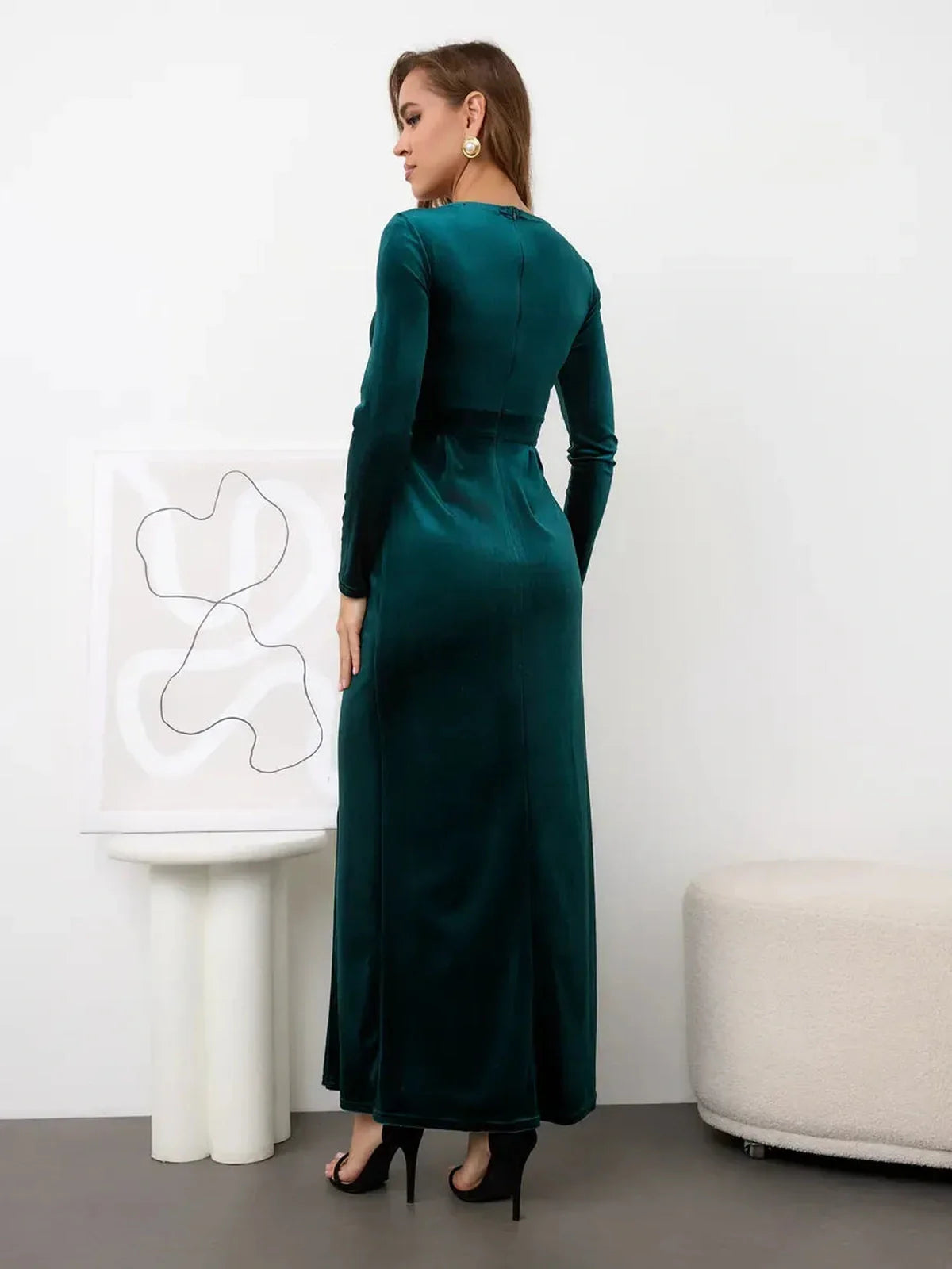 Elegant back view of the Verde Luxe Maxi Dress in emerald green velvet, showcasing its long sleeves and floor-length design.