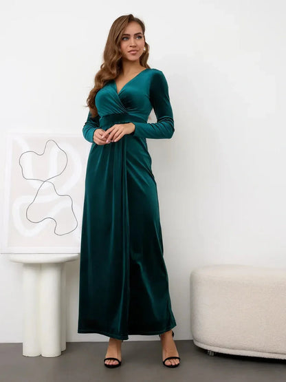 Model wearing Verde Luxe Maxi Dress in emerald velvet with wrap-effect bodice and thigh-high slit, elegant fashion statement.