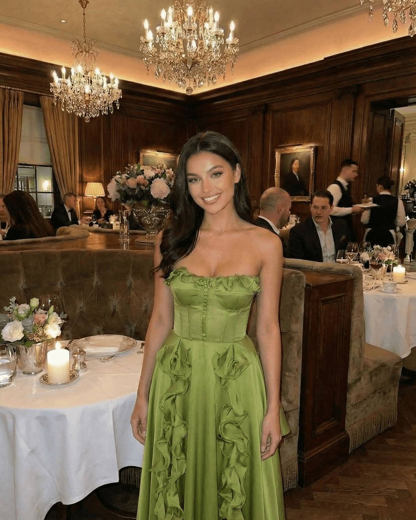 Elegant woman in a strapless Verdessa Maxi Dress by Lauven, featuring ruffles, in a luxurious restaurant setting.