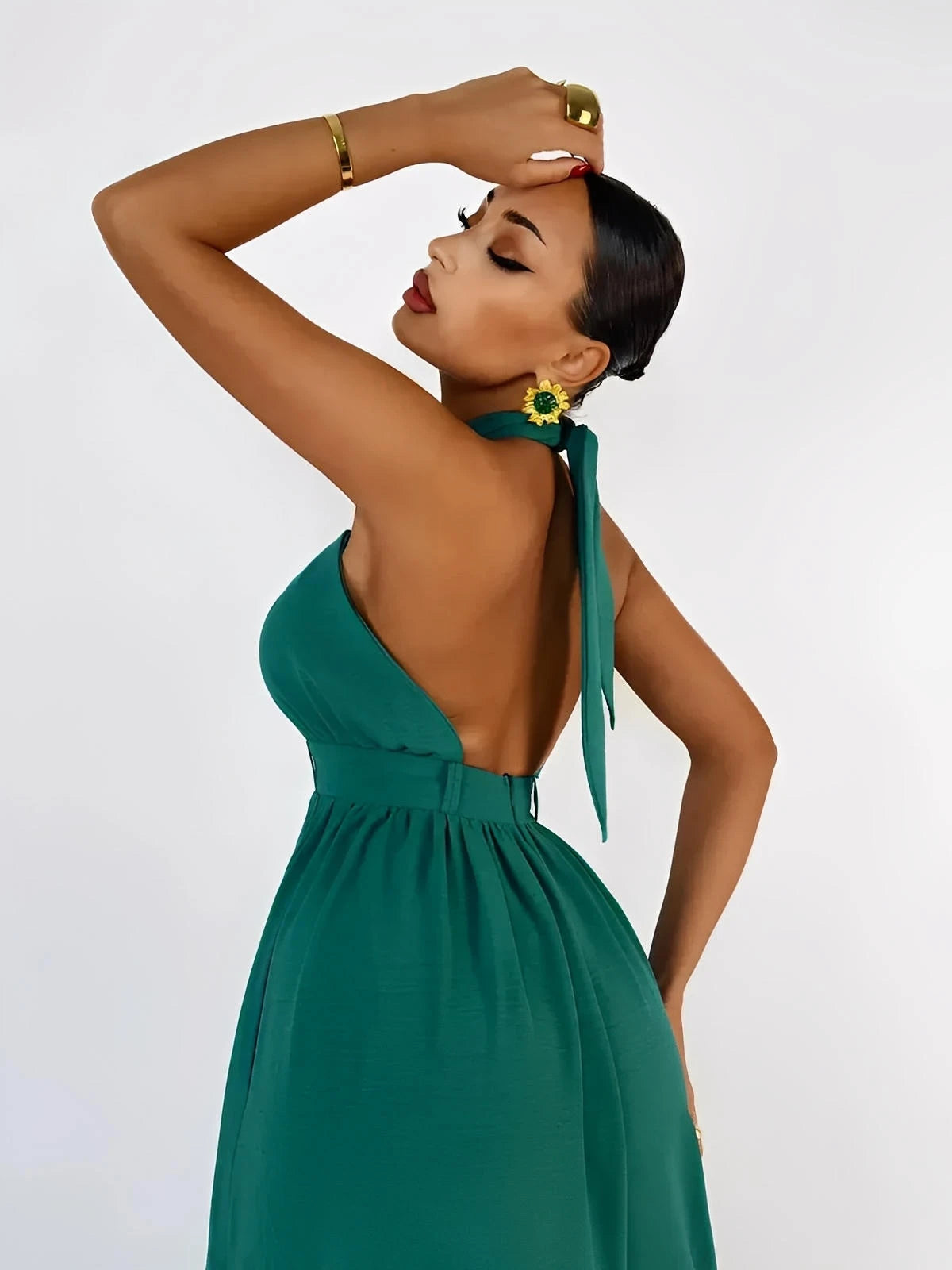 Model showcasing the Verona Jumpsuit, featuring a halter neck design and open back in rich emerald green.