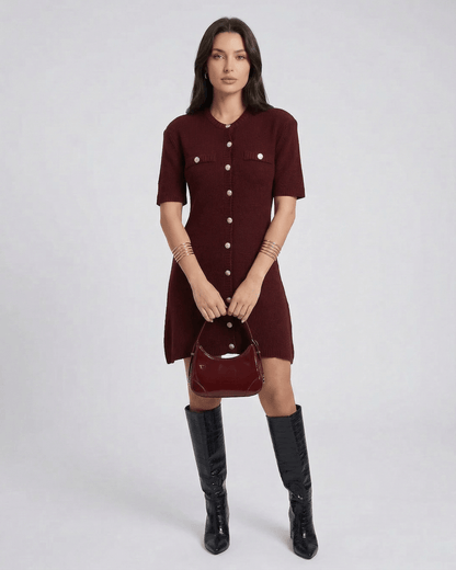 Model wearing Viera Mini Dress by Lauven in burgundy with button closure and stylish bag.