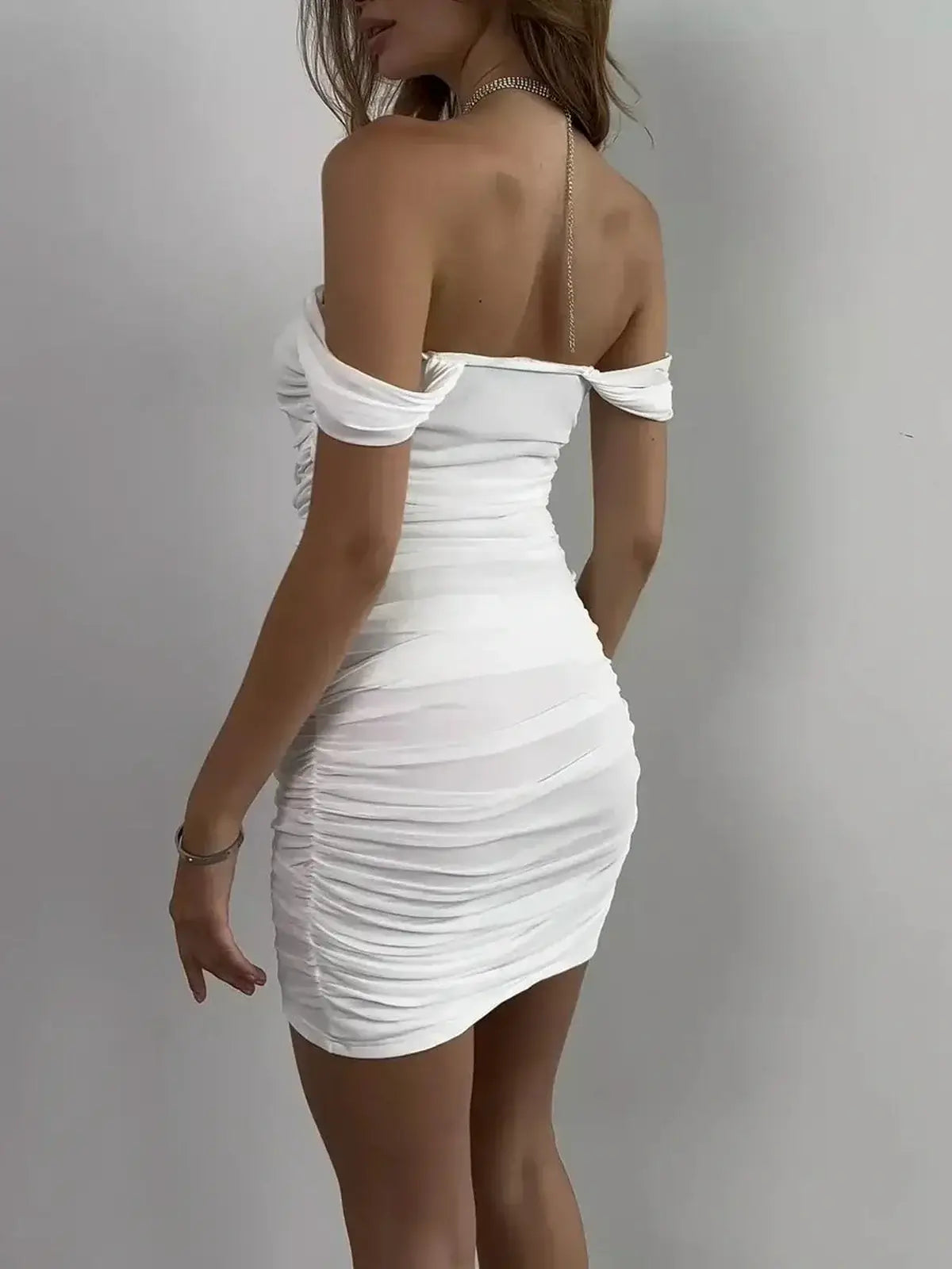Back view of a woman in a white off-shoulder mini dress with ruched detailing, perfect for summer occasions and parties.